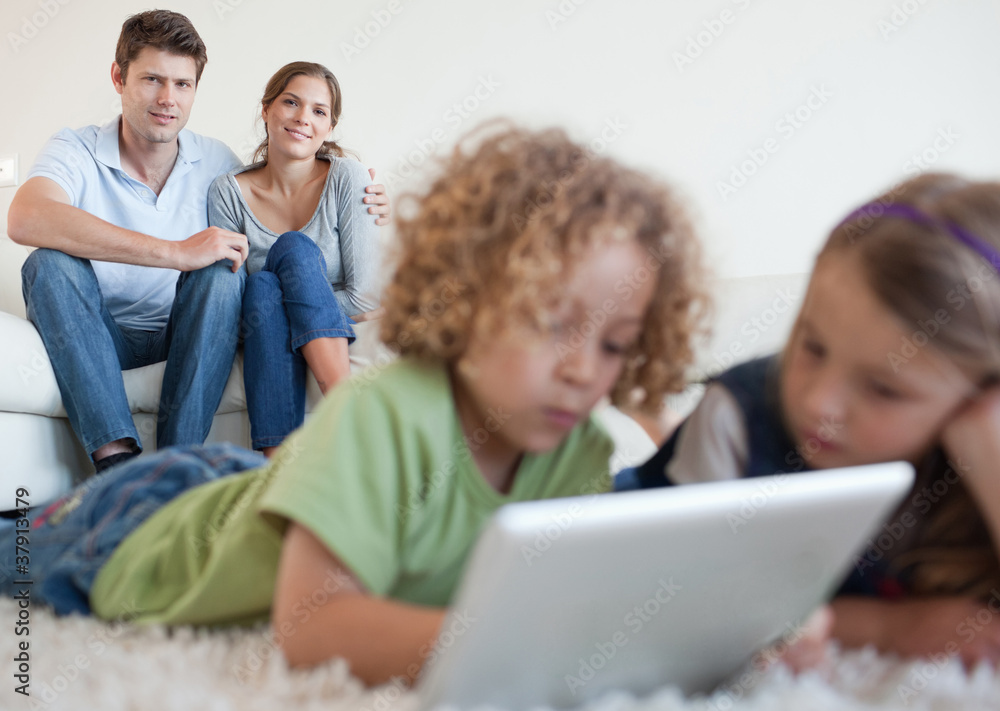 Cute children using a tablet computer while their happy parents Cute children using a tablet computer while their happy parents