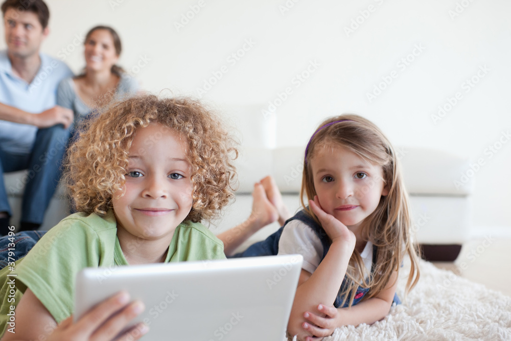 Happy children using a tablet computer while their happy parents Happy children using a tablet computer while their happy parents