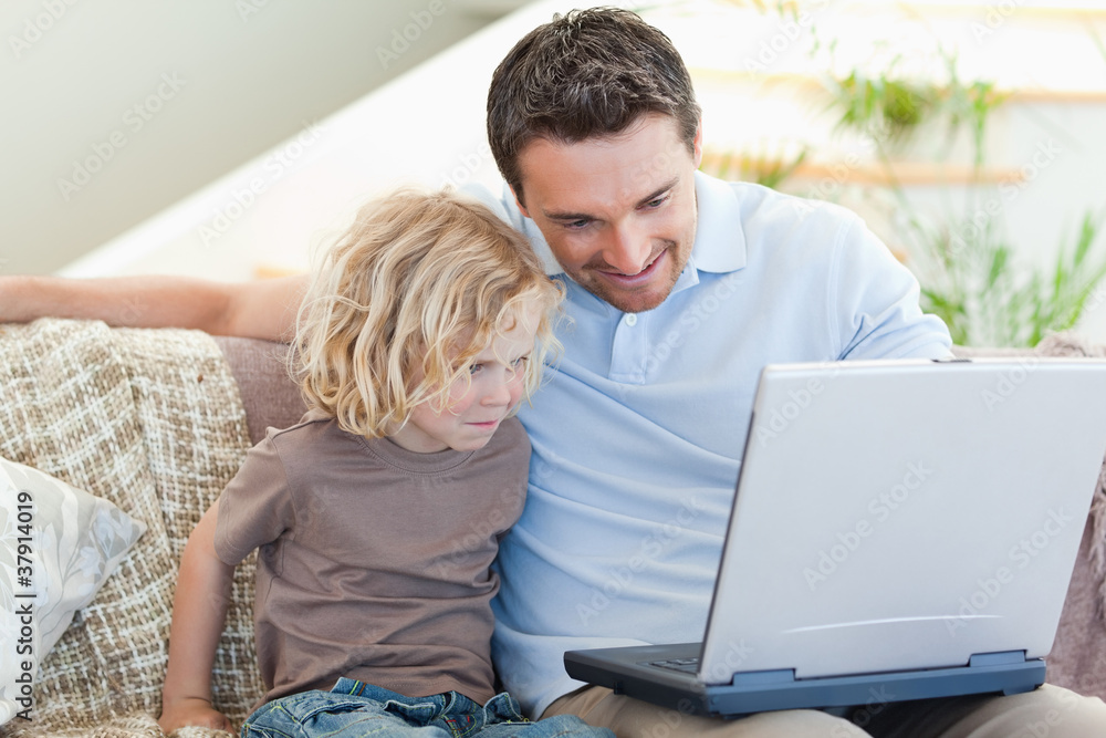 Fototapeta premium Father and son with laptop on the sofa