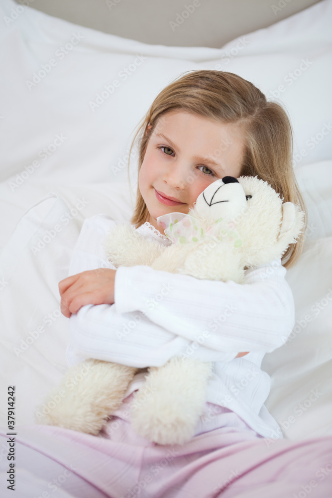 Girl embracing her teddy on the bed