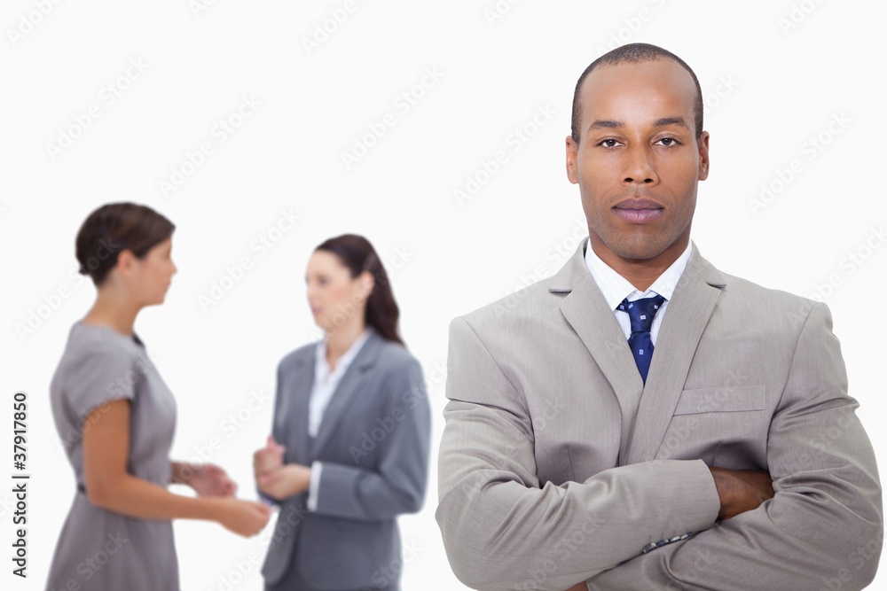 Businessman with arms folded and colleagues behind him Businessman with arms folded and colleagues behind him