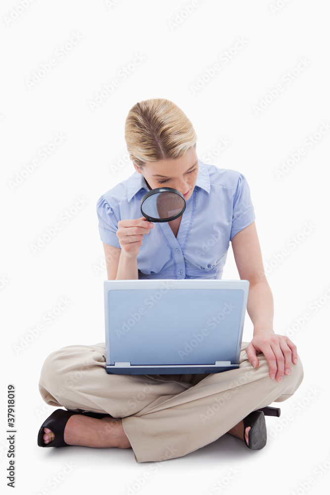 Woman using magnifier to look at her laptop Woman using magnifier to look at her laptop