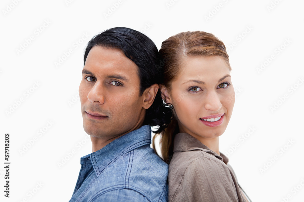 Side view of young couple standing back to back Side view of young couple standing back to back