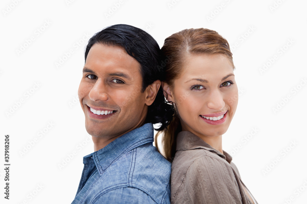 Side view of smiling couple standing back to back Side view of smiling couple standing back to back