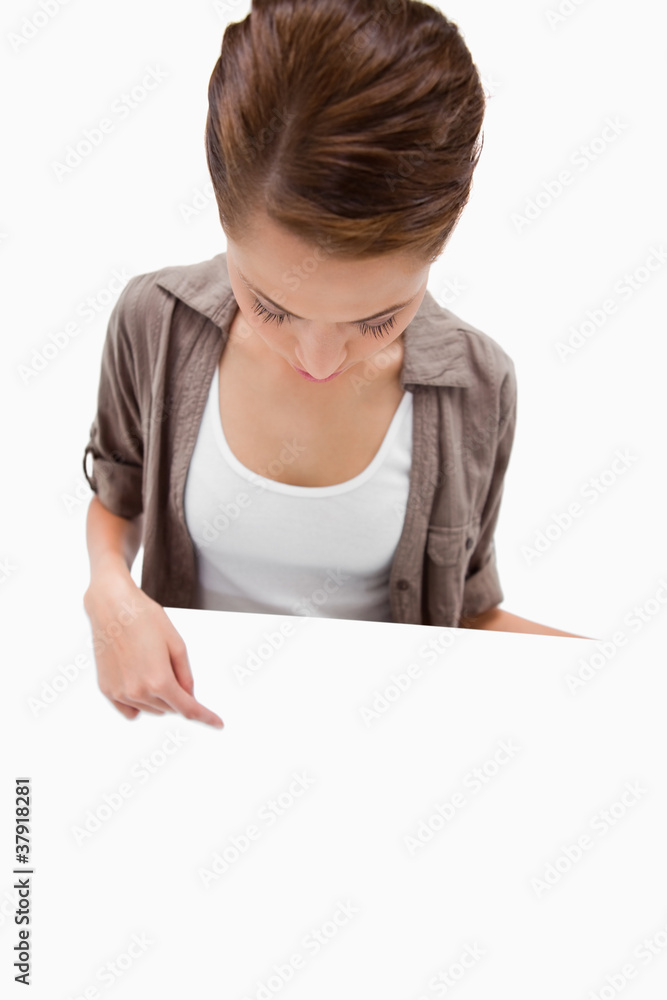 Woman pointing down at blank signboard in her hand Woman pointing down at blank signboard in her hand