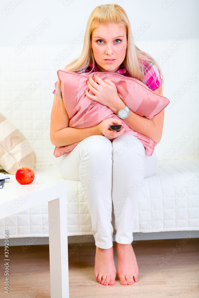 Experiencing young woman sitting on couch and watching TV Experiencing young woman sitting on couch and watching TV