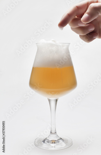 birra con schiuma e mano