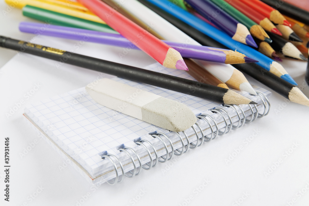 Fototapeta premium Multi-colored pencils and notepad on a white background