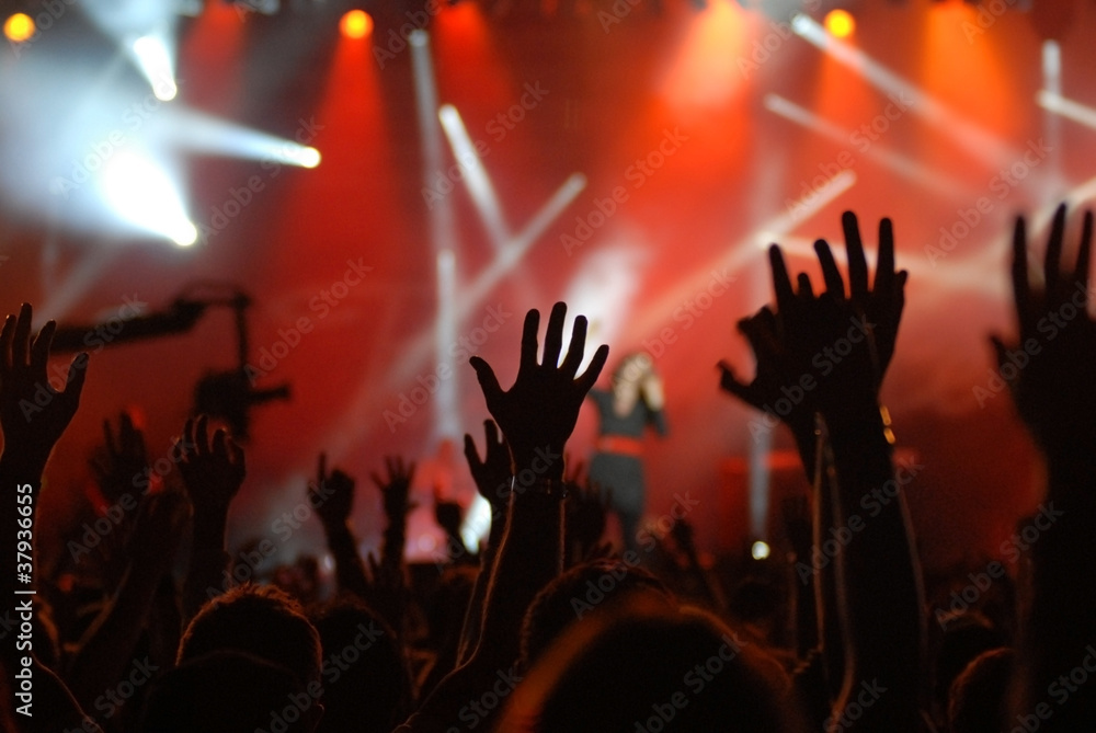 raised hands at concert with red lighting