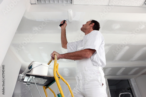 Tradesman painting a ceiling photo