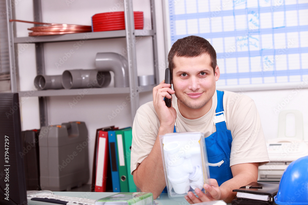 Man on telephone checking a plumbing part Man on telephone checking a plumbing part