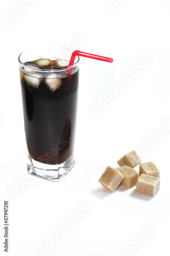 Glass of cola soda drink with sugar cubes