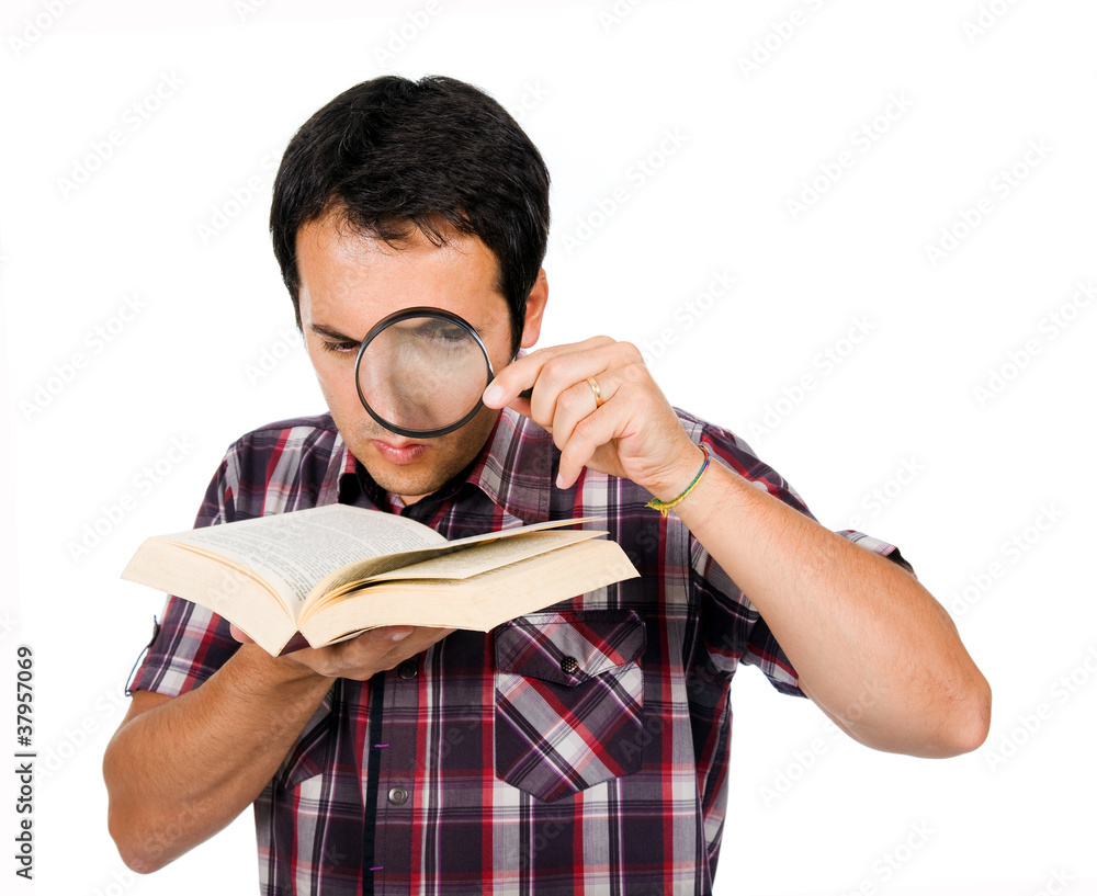 Young man reading a interesting book with magnifying glass, isol Young man reading a interesting book with magnifying glass, isol