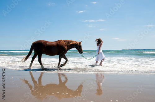 Girl exercising horse at the beach