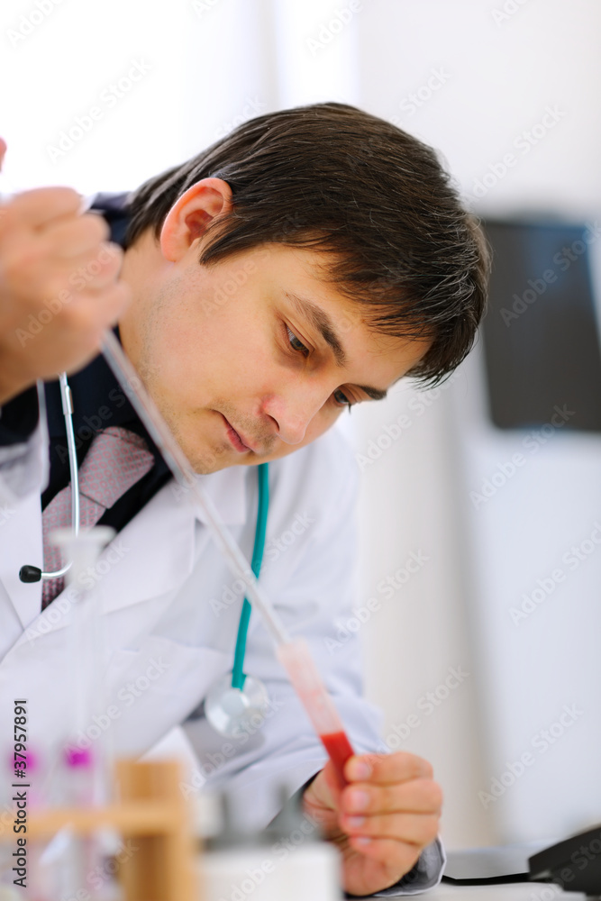 Naklejka premium Researcher working with test tube at cabinet