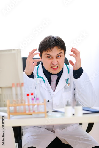 Stressed medical doctor sitting at office table