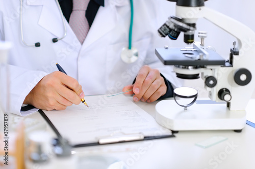 Close-up on hands of medical doctor working at office table