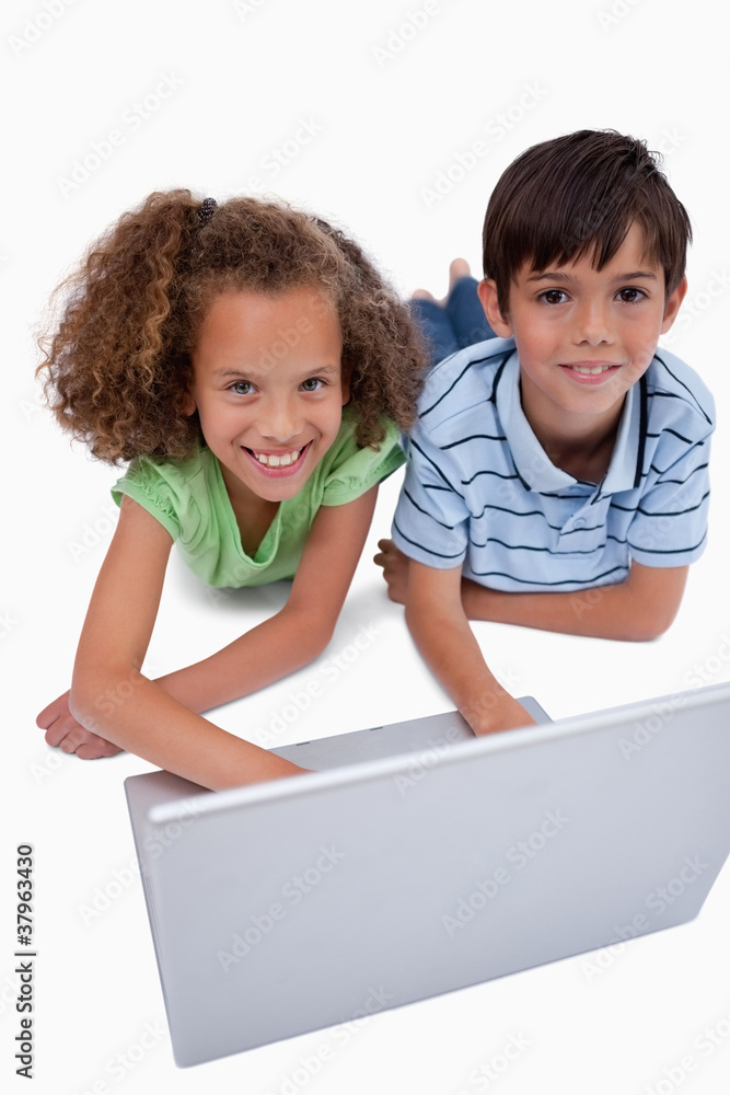 Portrait of children using a notebook while lying on the floor Portrait of children using a notebook while lying on the floor