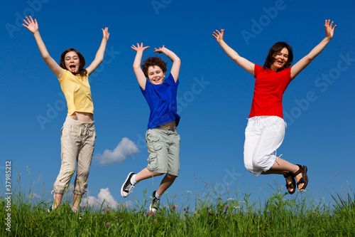 Active family - mother and kids jumping outdoor