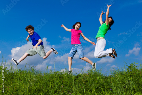 Active family - mother and kids jumping outdoor