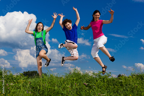 Active family - mother and kids jumping outdoor