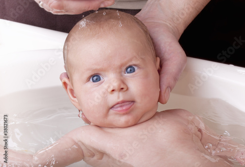 father bathing his newborn baby daughter for the first time.