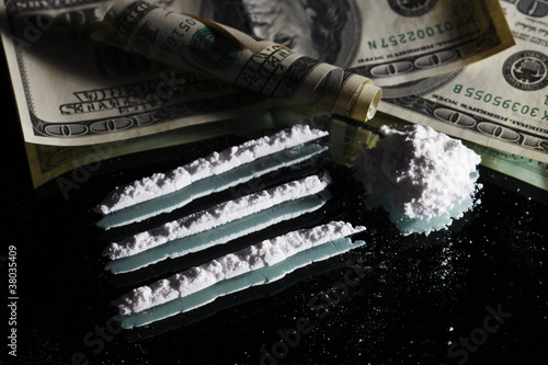 Cocaine drugs heap still life on a mirror with rolled 100 dollar