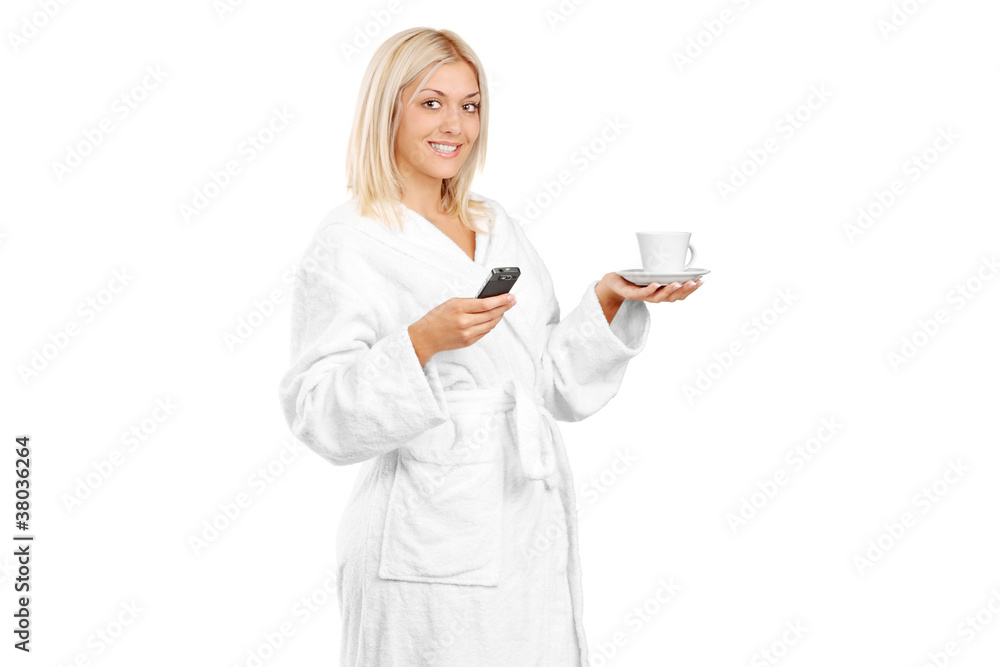 A young woman in bathrobe holding a coffee cup and mobile phone A young woman in bathrobe holding a coffee cup and mobile phone