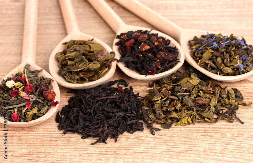 Different kinds of dry green and black tea in spoons Different kinds of dry green and black tea in spoons