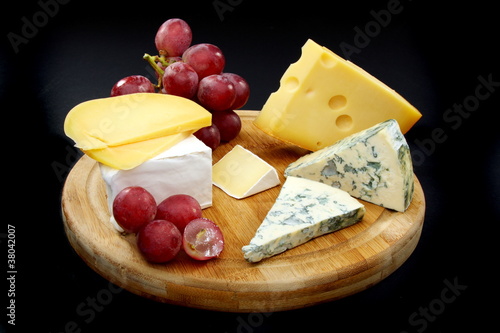 Cheese and grapes on a wooden board.