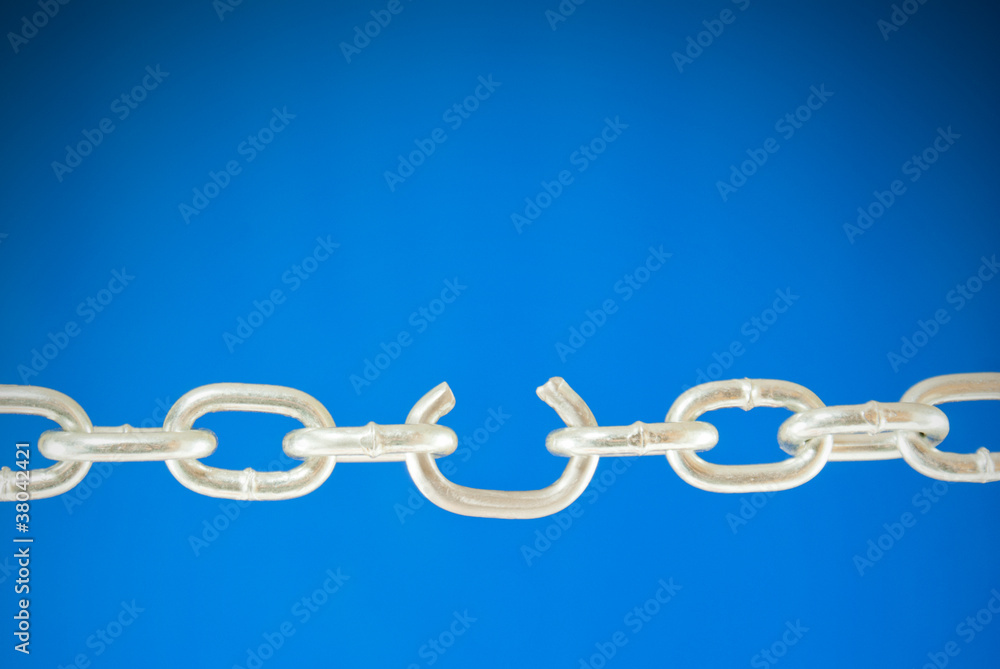 Steel chain with a broken link over blue background