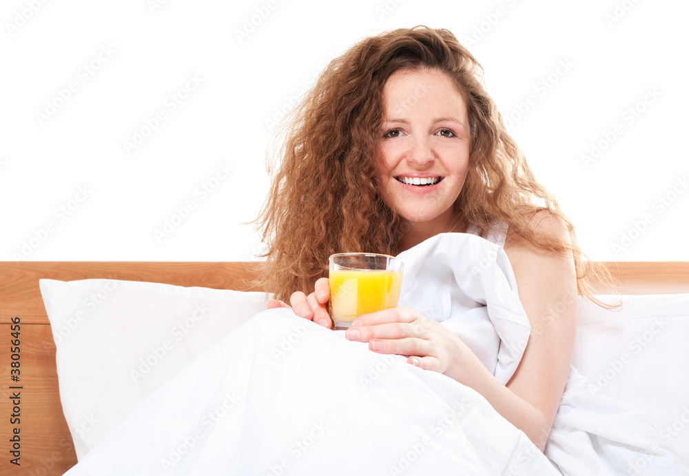Happy redhead woman in bed with glass of orange juice