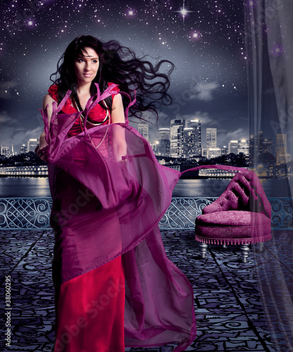 stunning woman in eveningdress on a terrace under a starry sky / photo