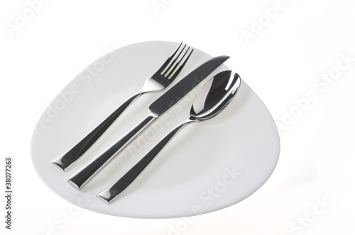 Fork, spoon and  knife on a plate over white