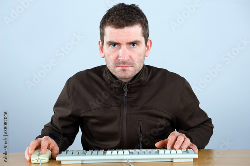 man is looking grimmly in the computer photo