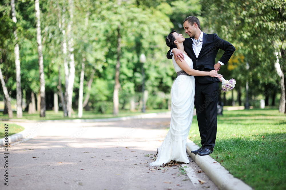 Bride and groom walking in a summer park Bride and groom walking in a summer park