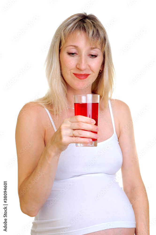 The pregnant woman holds a juice glass The pregnant woman holds a juice glass