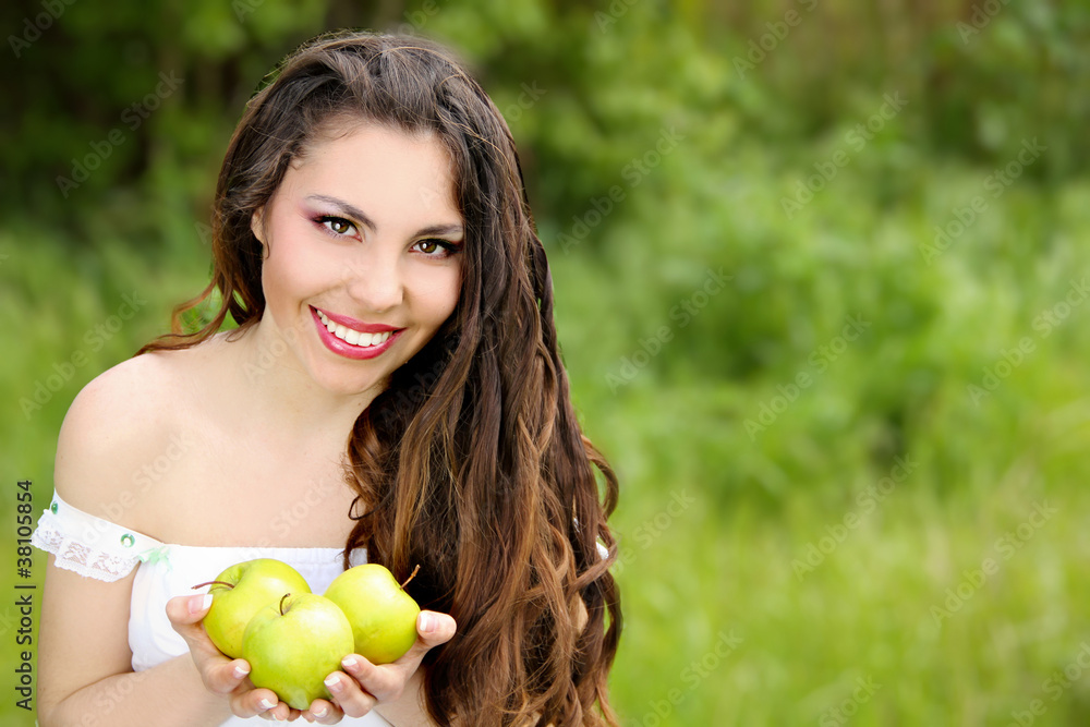 Beautiful young woman holding apples on grass outdoors backgroun Beautiful young woman holding apples on grass outdoors backgroun