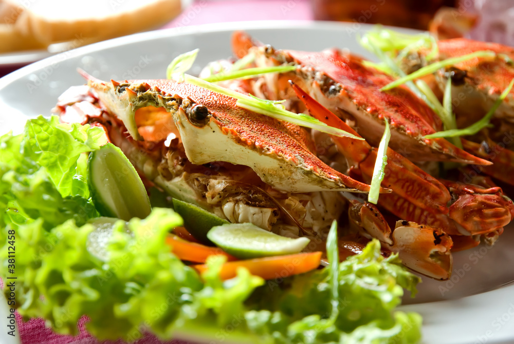 three large red crabs with salad and lime