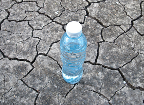 Canvas Print Cracked ground with water in a bottle