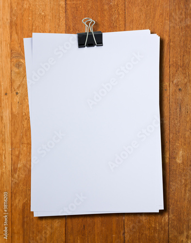 Black clip and White blank note paper hang on wood pane