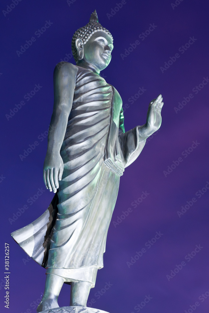 Back of walking Buddha statue in twilight tilted Back of walking Buddha statue in twilight tilted