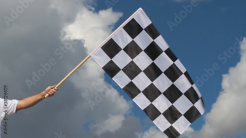 Hand holding a checkered flag on a raceway photo