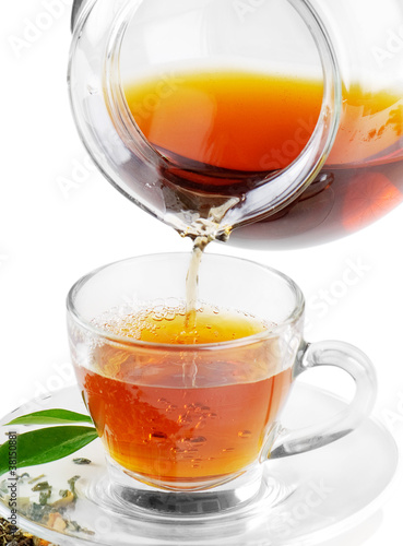 Tea being poured into tea cup isolated on a white background