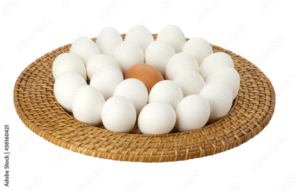 Eggs on a wicker tray with one brown egg Eggs on a wicker tray with one brown egg