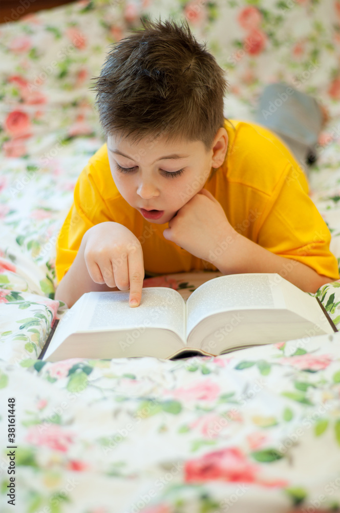 A boy reads a book in bed A boy reads a book in bed