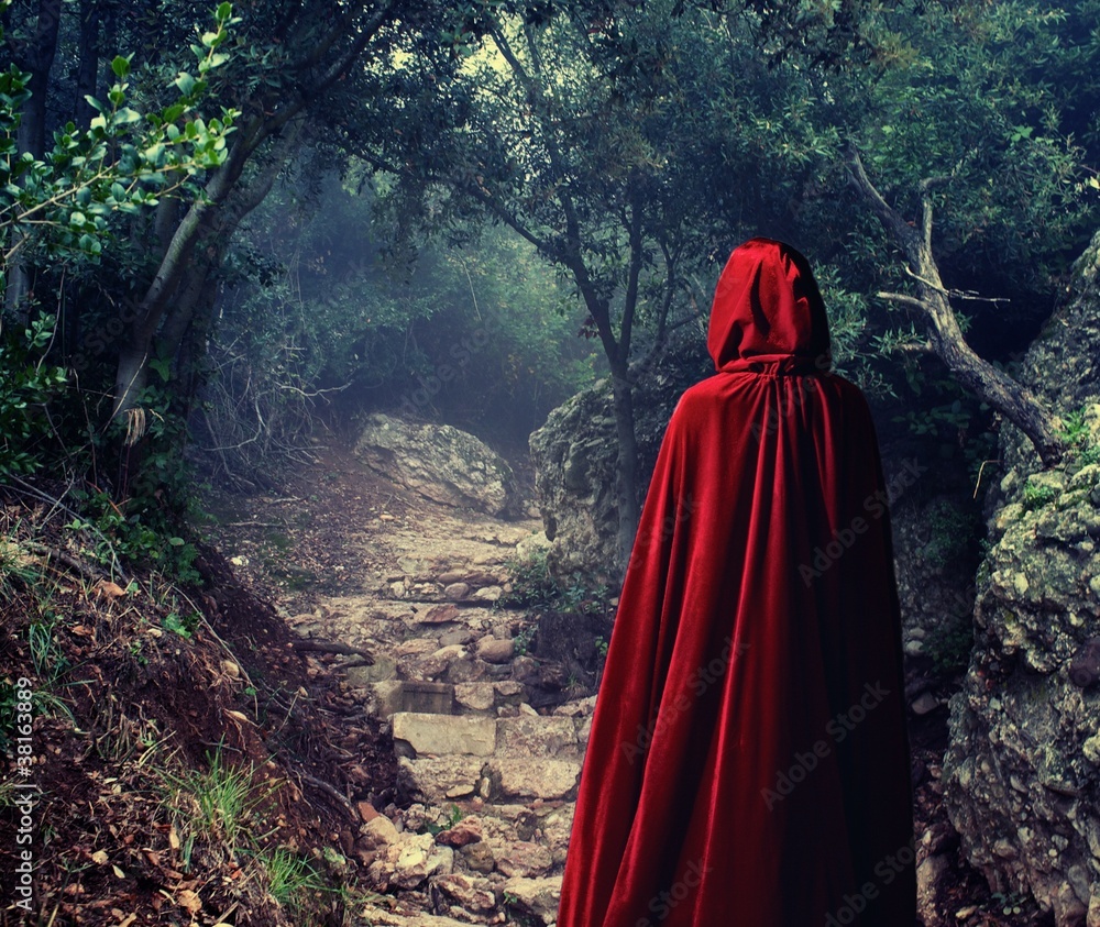 Person wearing red cloak in a forest. Person wearing red cloak in a forest.