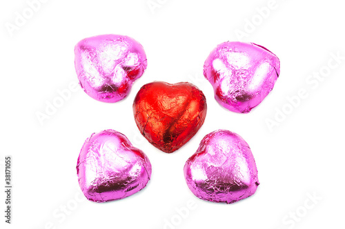 Wrapped chocolate hearts on white background