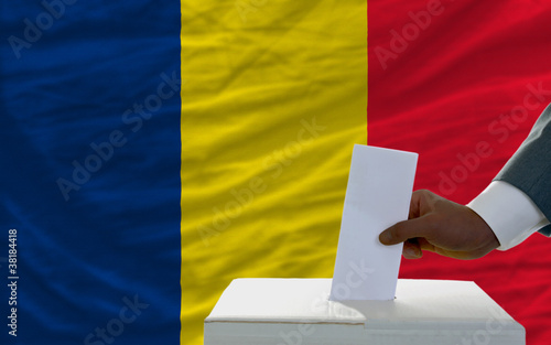 man voting on elections in front of national flag of chad