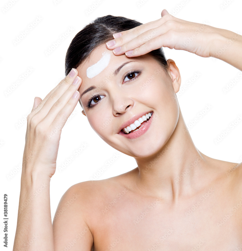 happy woman applying cosmetic cream on forehead happy woman applying cosmetic cream on forehead